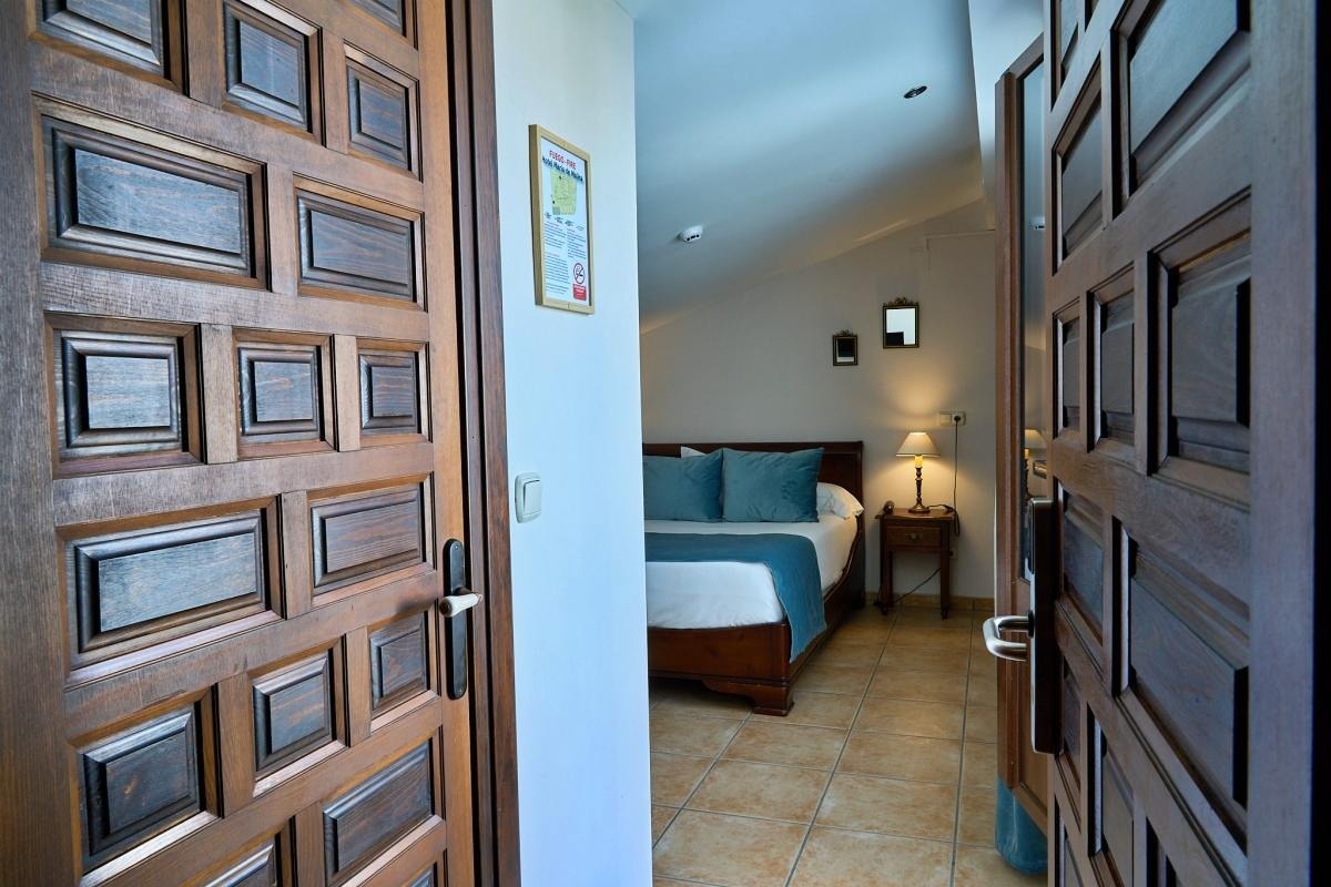 una puerta de madera que conduce a una habitación con una cama y una lámpara