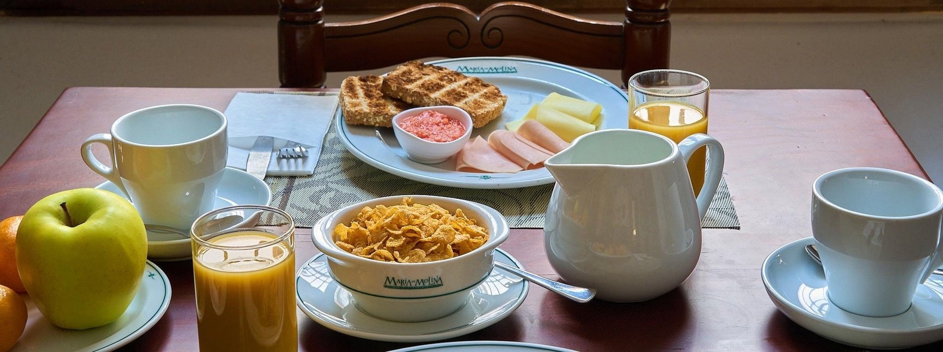 a table with a bowl of cereal and a pitcher of orange juice