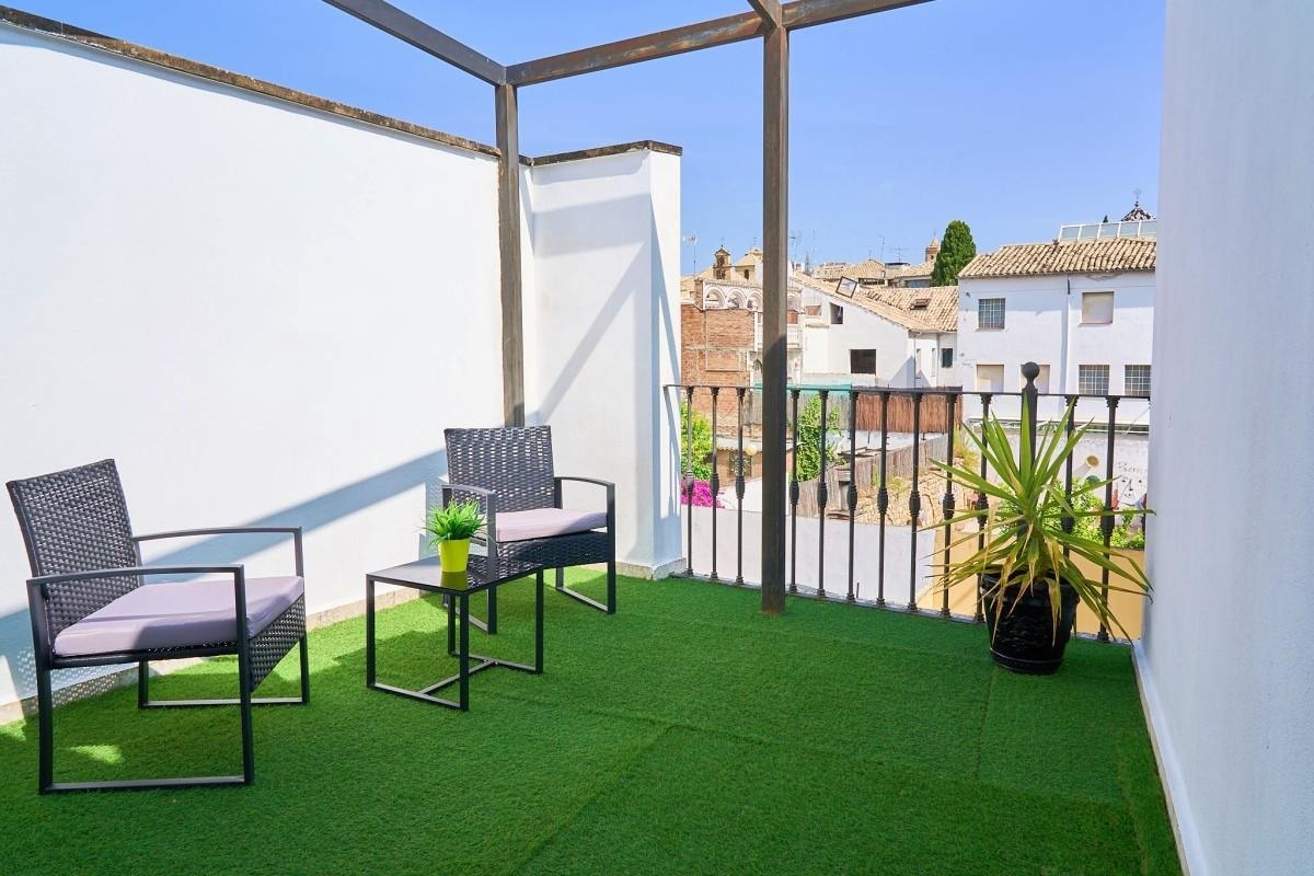 un balcón con sillas y una mesa con una planta encima