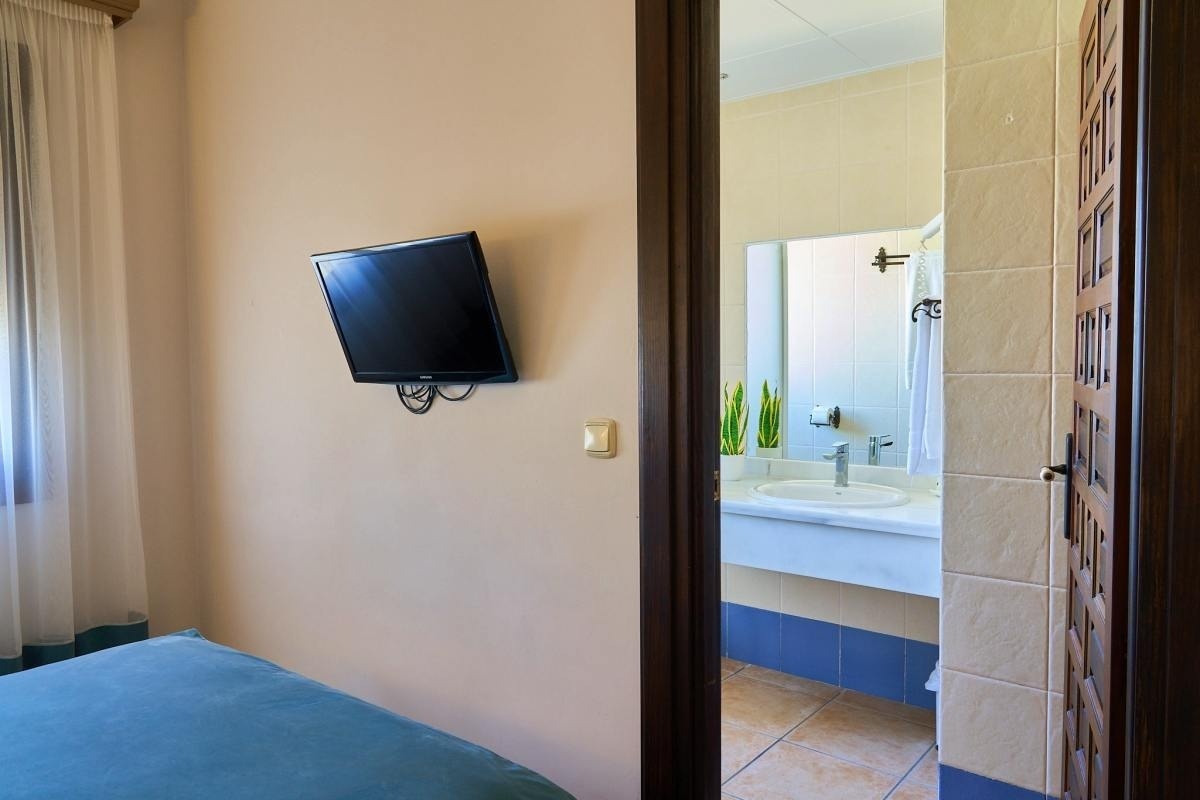 una puerta que conduce a un baño con un lavabo y una televisión