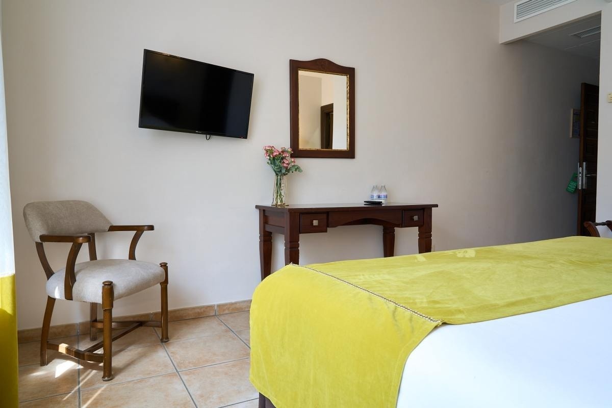 una habitación con una cama , una silla , un escritorio y una televisión