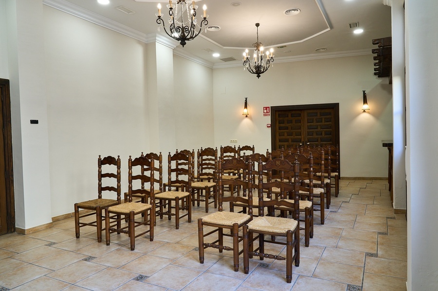 una habitación llena de sillas de madera y un candelabro