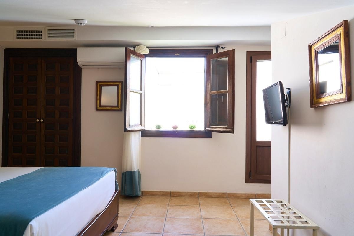 una habitación con una cama y una televisión en la pared