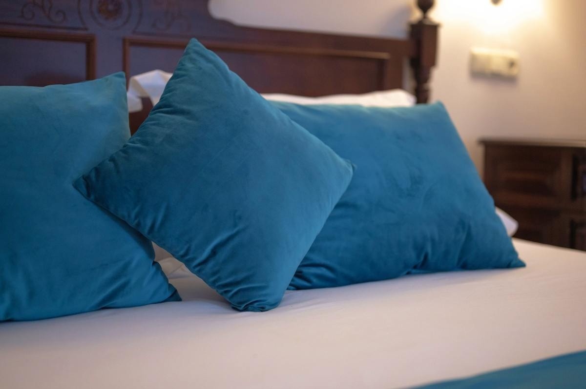 dos almohadas azules están sobre una cama blanca