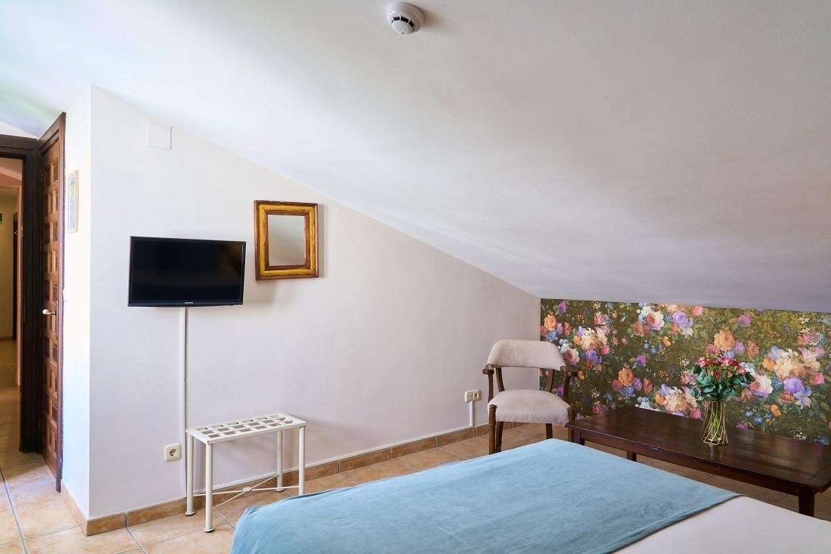 una habitación con una cama y una televisión y un jarrón de flores