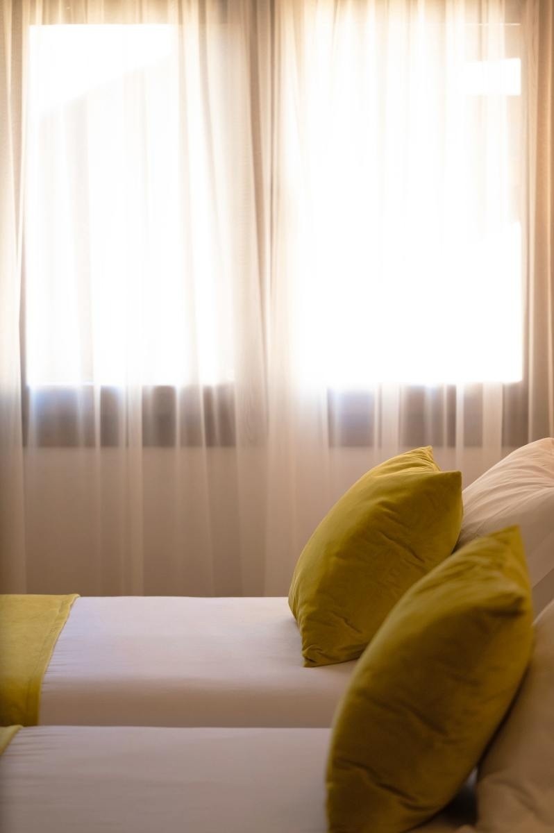 una habitación con dos camas y dos almohadas amarillas frente a una ventana