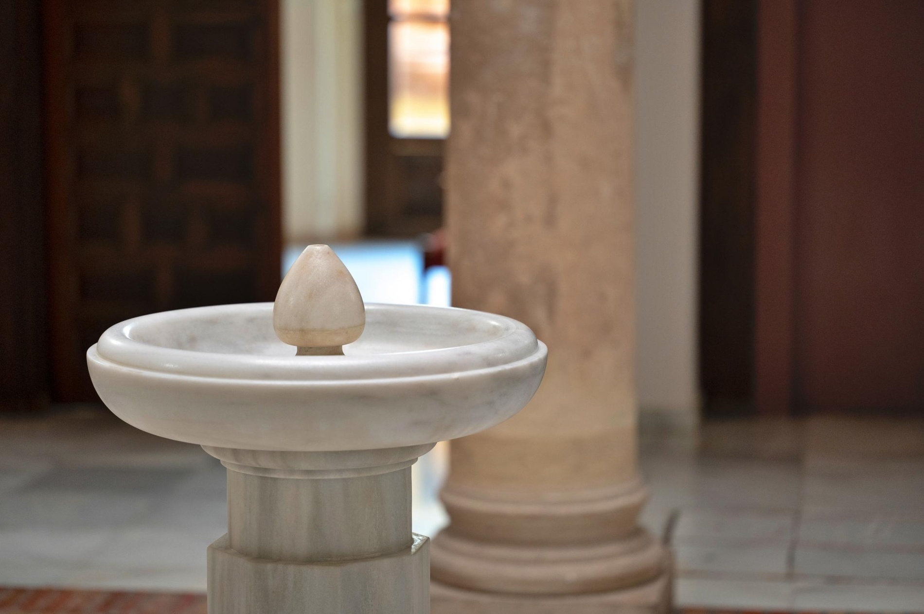 a white marble fountain with a candle on top