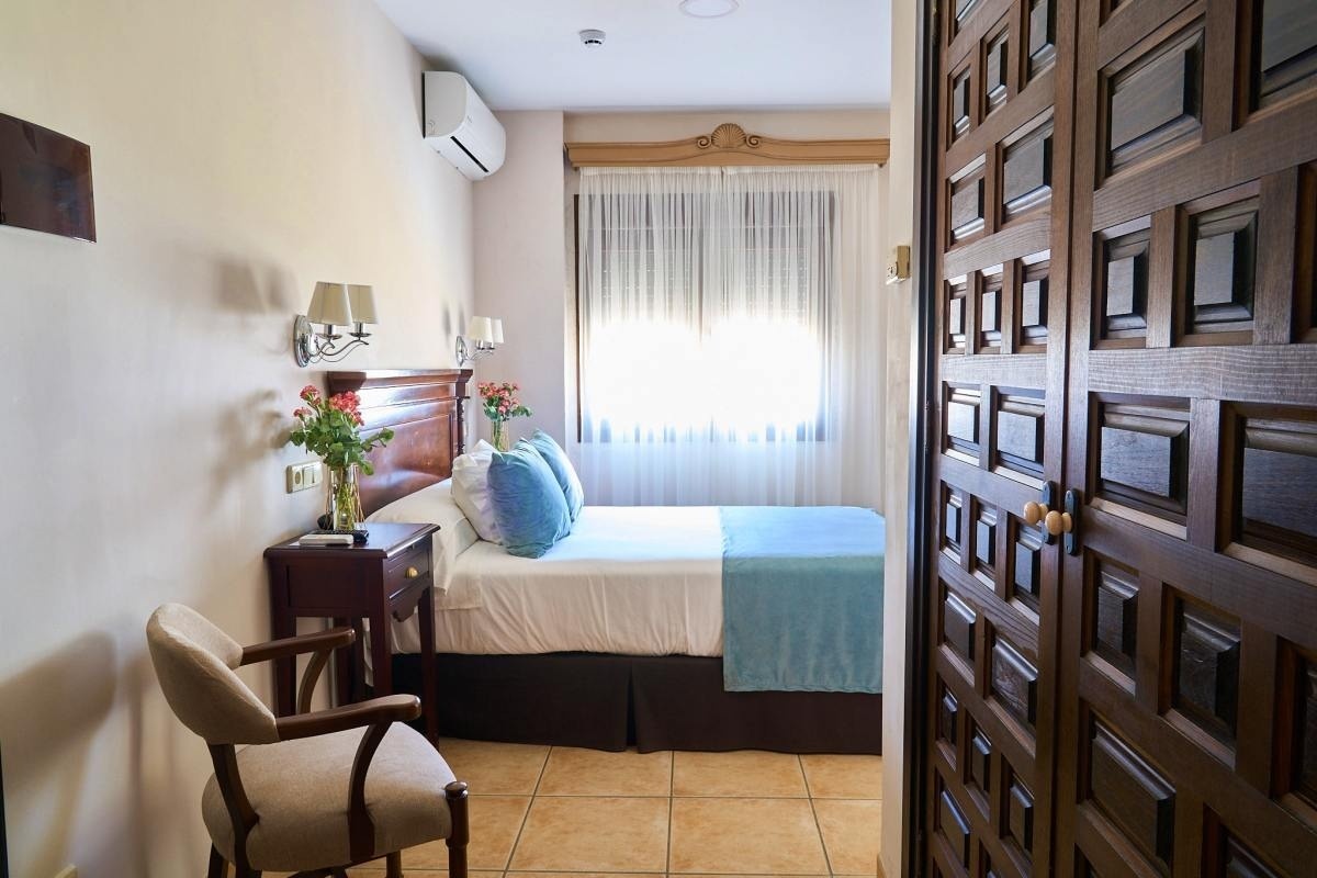 una puerta de madera conduce a una habitación con una cama y una silla