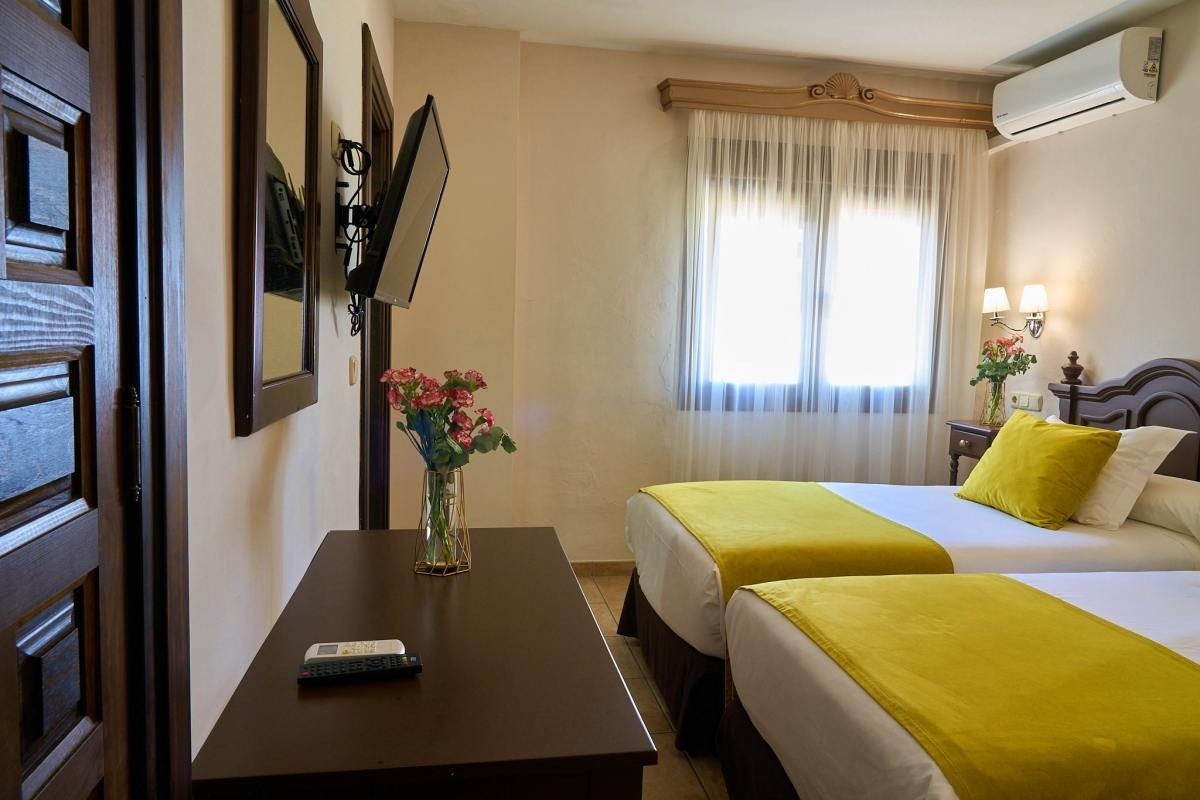 una habitación con dos camas y una televisión en la pared