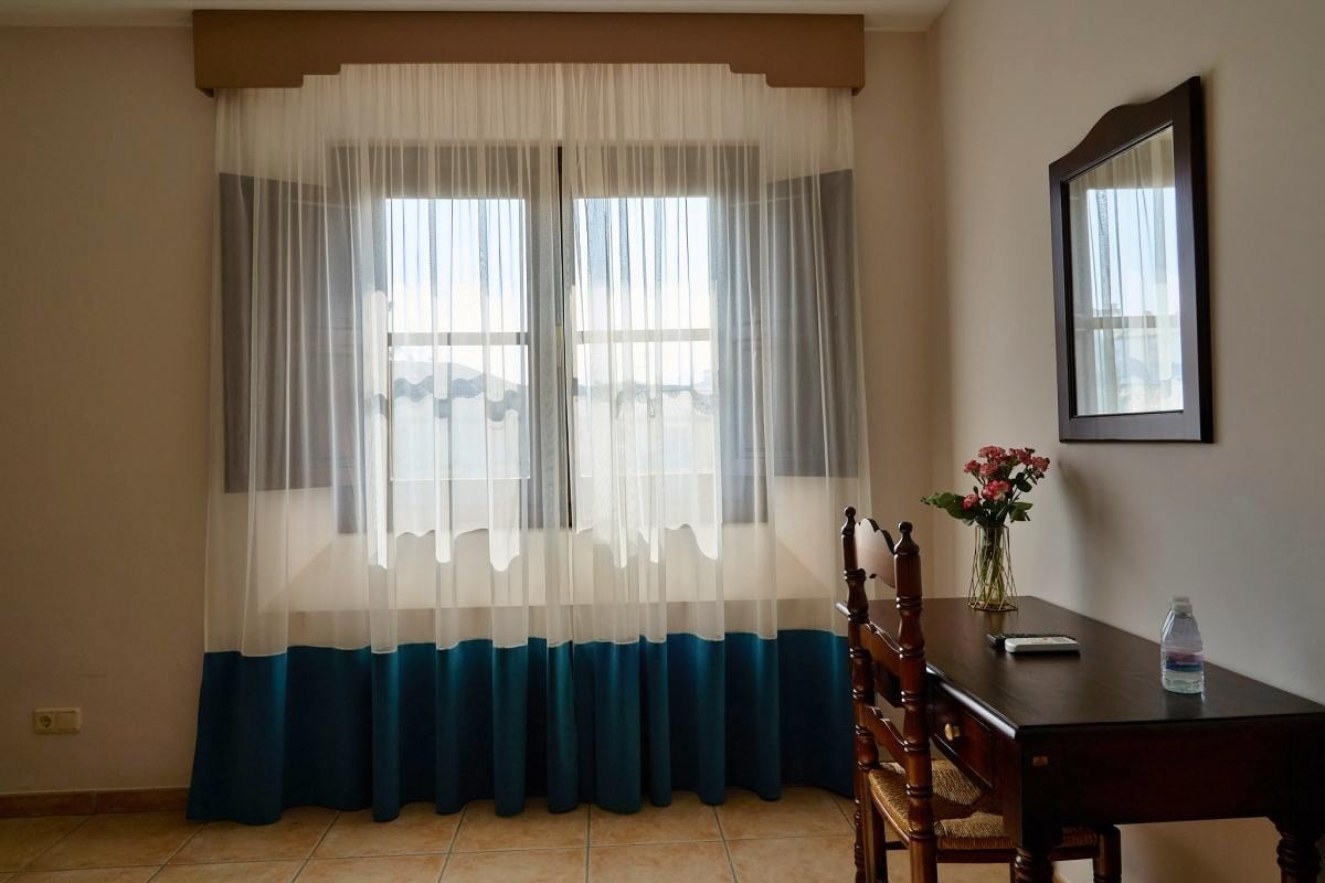 una habitación con una mesa y una ventana con cortinas azules y blancas