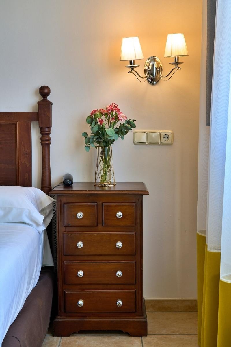 una cómoda de madera con un jarrón de flores encima