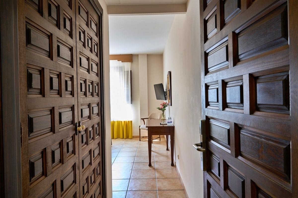 una puerta de madera que conduce a una habitación con una mesa y una televisión