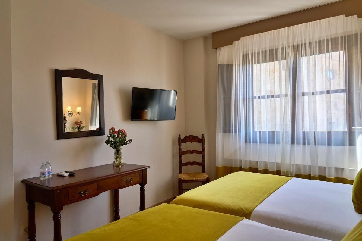 una habitación con dos camas y una televisión en la pared