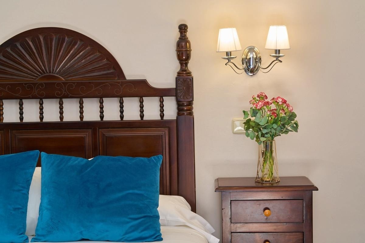 una cama con dos almohadas azules y una mesita de noche con un jarrón de flores