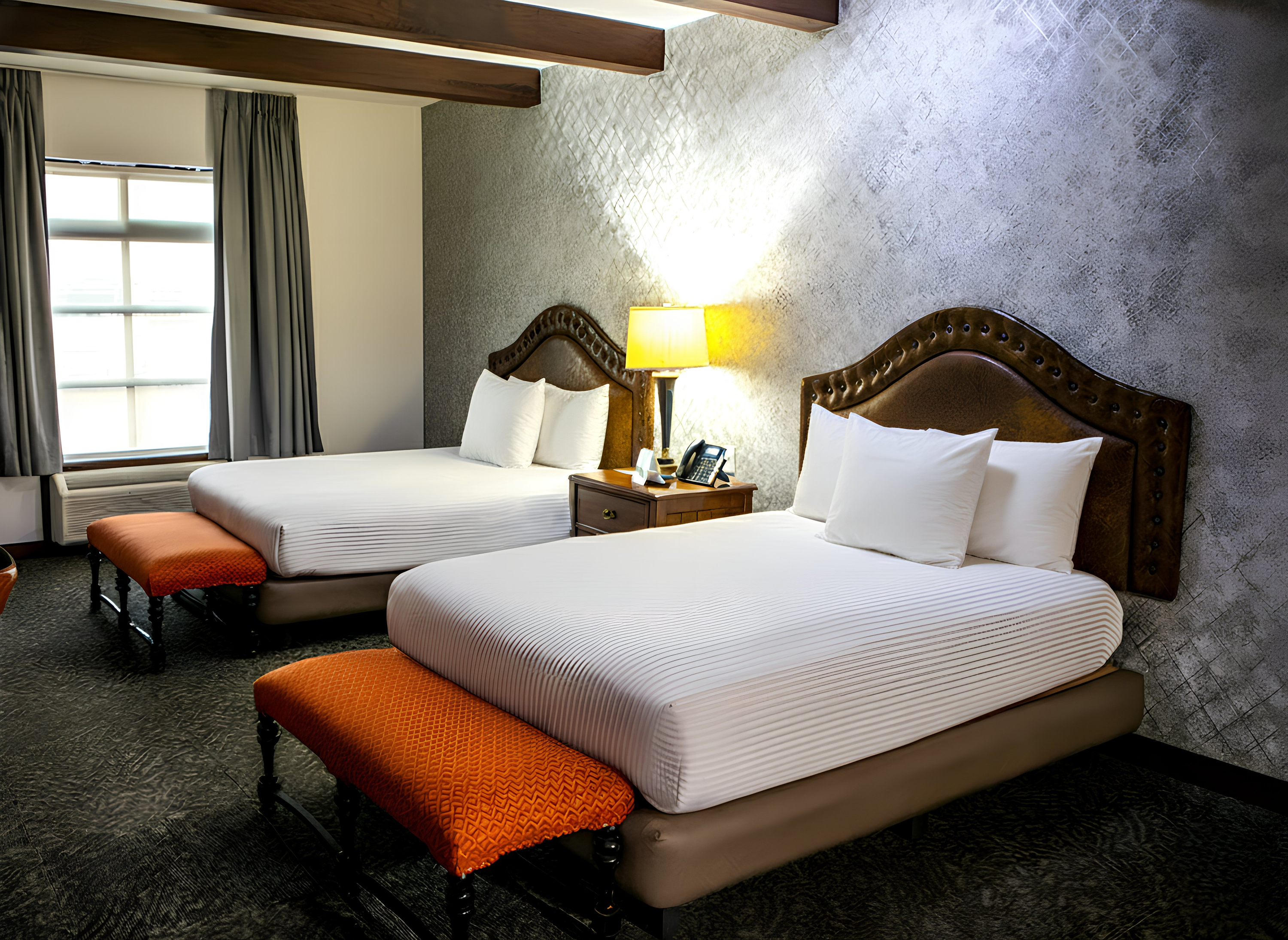 Habitación Maria Bonita Corporativa: dos camas, mesas de noche y asientos naranjas.Habitación de hotel Maria Bonita Corporativa con dos camas, ropa de cama blanca y acentos marrones.