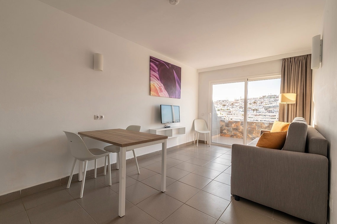 ein Wohnzimmer mit einem Tisch und Stühlen und einem Fernseher