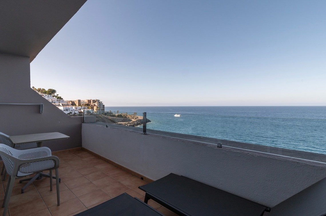 ein Balkon mit zwei Stühlen und einem Tisch mit Blick auf das Meer