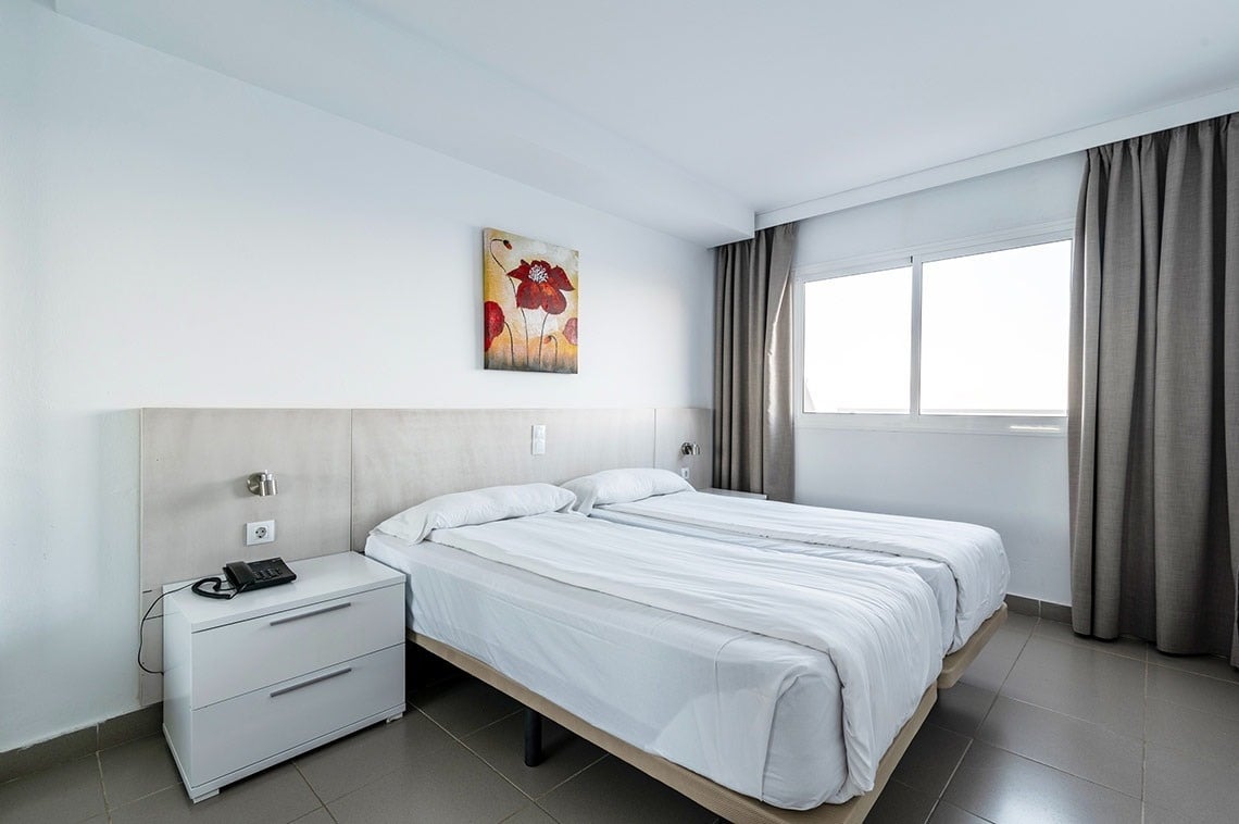 una habitación con dos camas y una pintura de flores en la pared