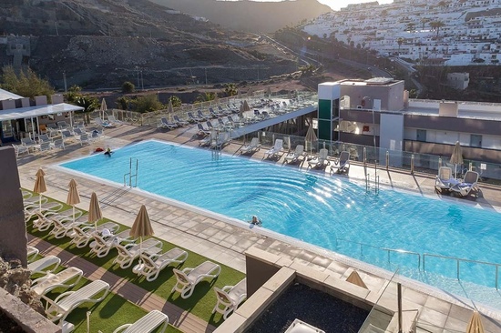 a large swimming pool surrounded by chairs and umbrellas