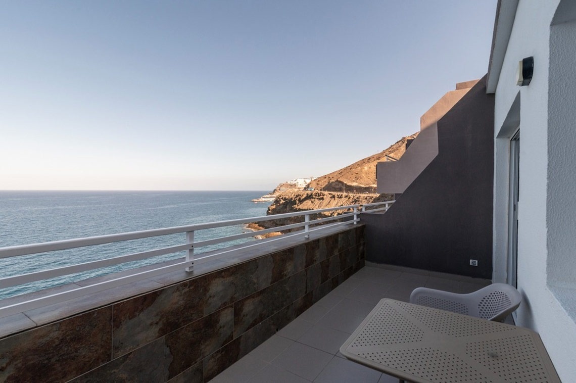 ein Balkon mit einem Tisch und einem Stuhl mit Blick auf das Meer