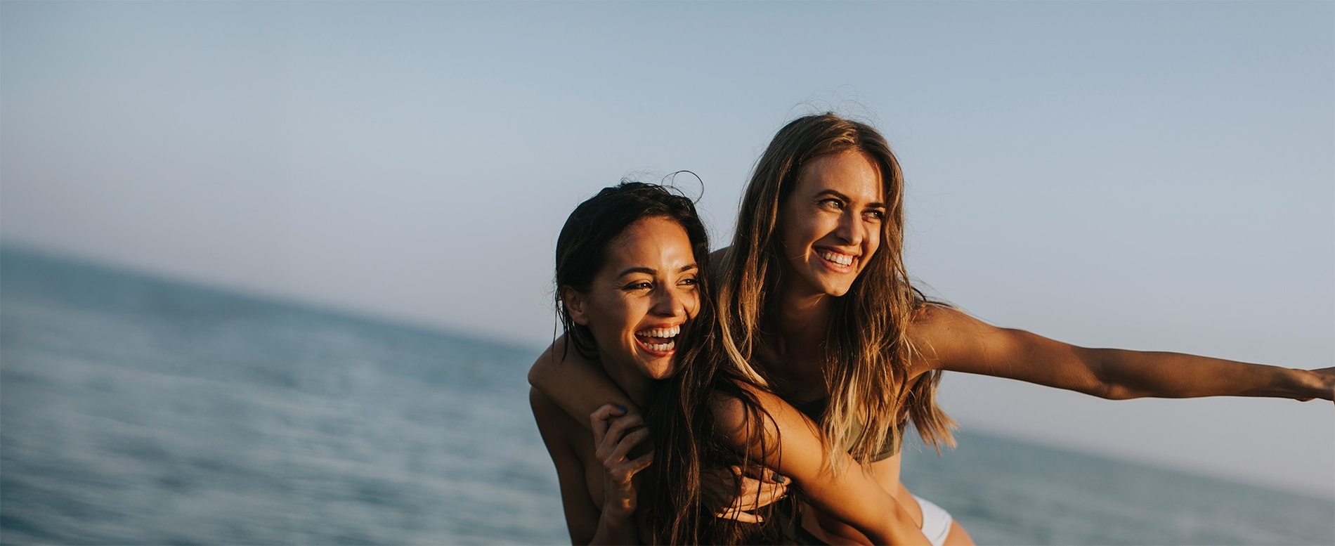 eine Frau trägt eine andere Frau auf dem Rücken und lächelt