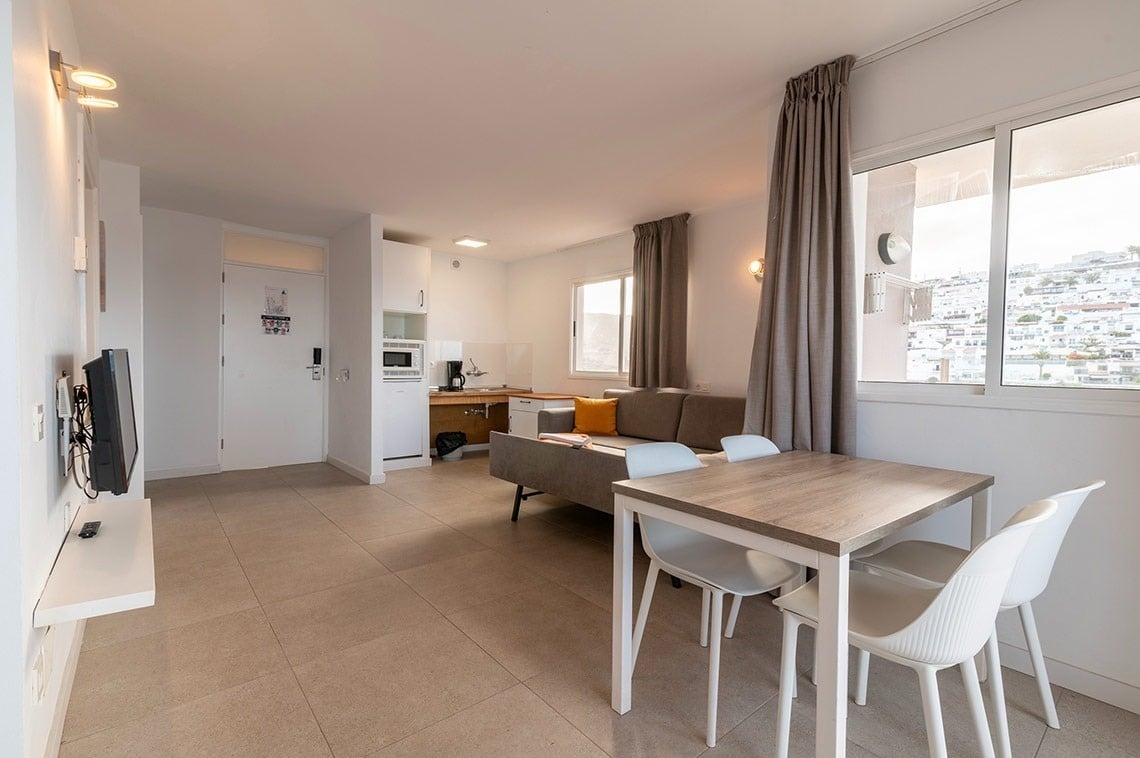 ein Wohnzimmer mit einem Tisch und Stühlen und einem Fernseher