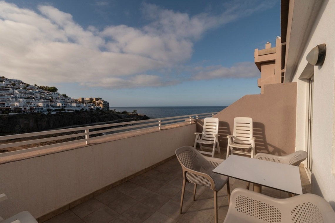 ein Balkon mit Tisch und Stühlen mit Blick auf das Meer