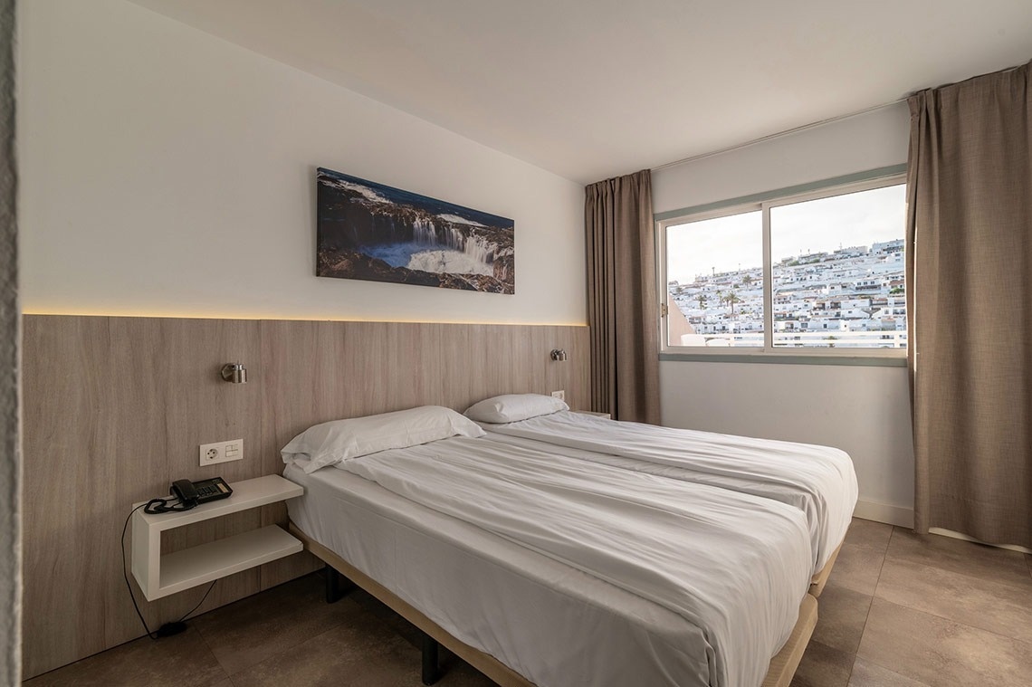 ein Schlafzimmer mit zwei Betten und einem Bild eines Wasserfalls an der Wand