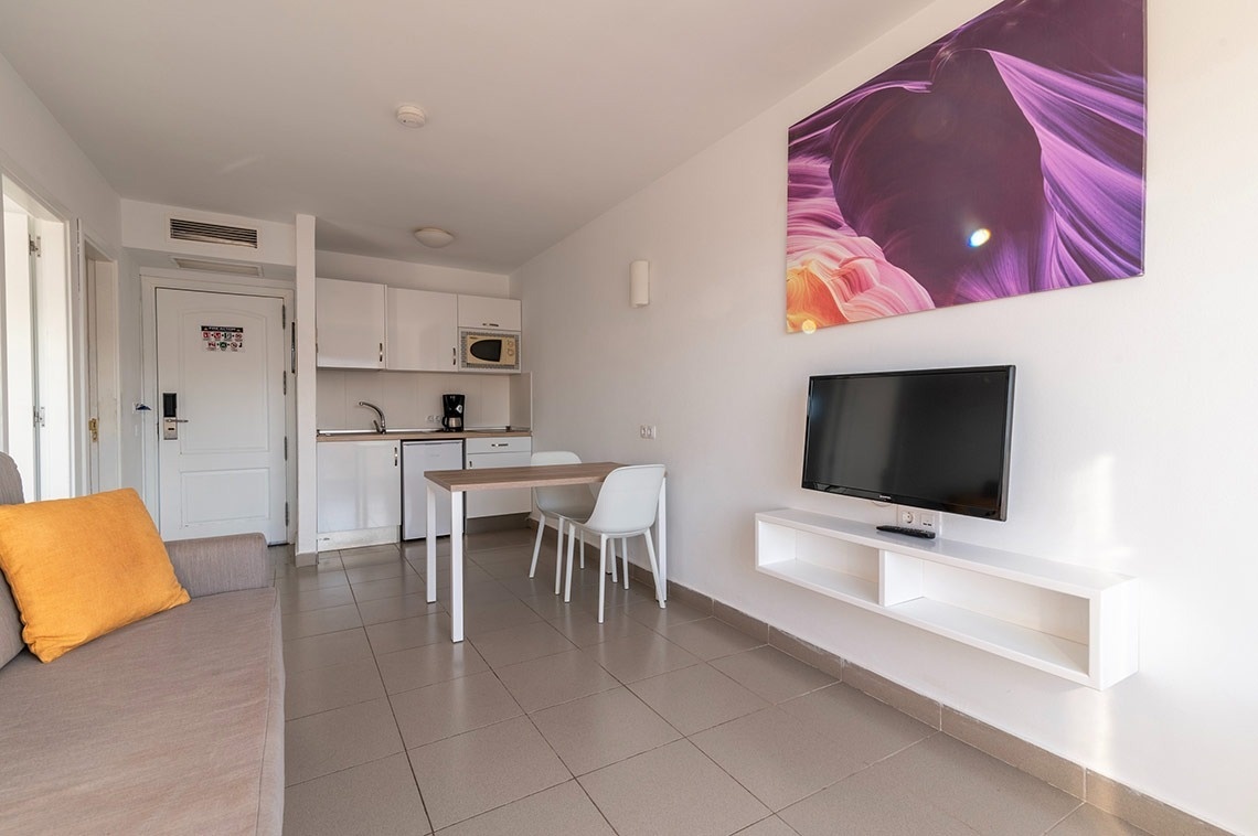 ein Wohnzimmer mit einem Fernseher und einem Bild an der Wand