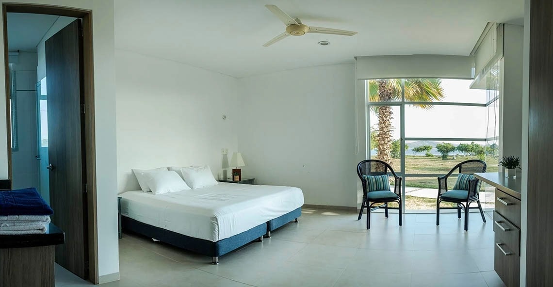 Room with sea view at Marina Puerto Velero, queen bed and two chairs.