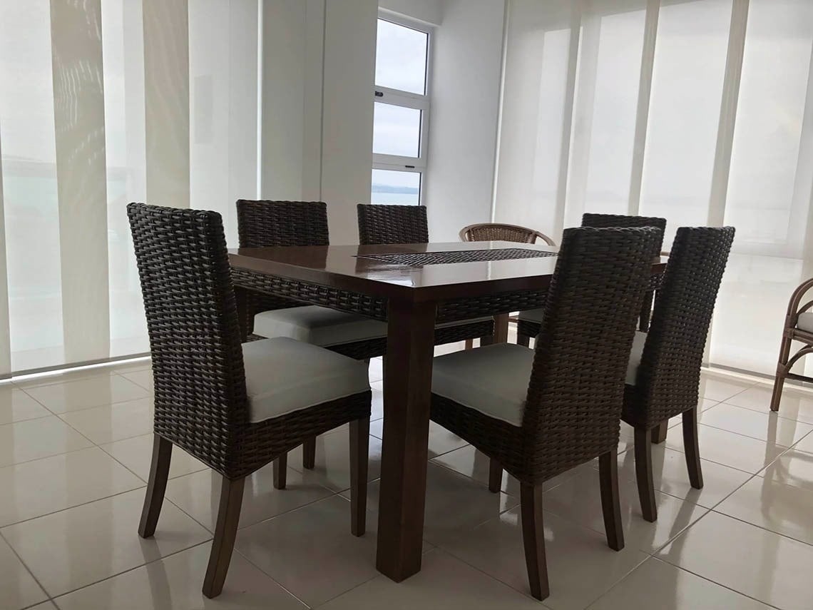 Elegant dining room at Marina Puerto Velero with rattan chairs and wooden table.