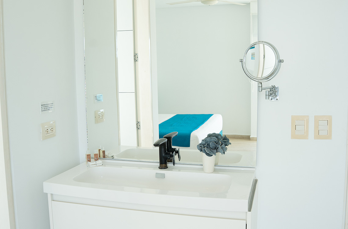 Espejo de aumento y tocador moderno con grifería negra en baño de hotel. Marina Puerto Velero