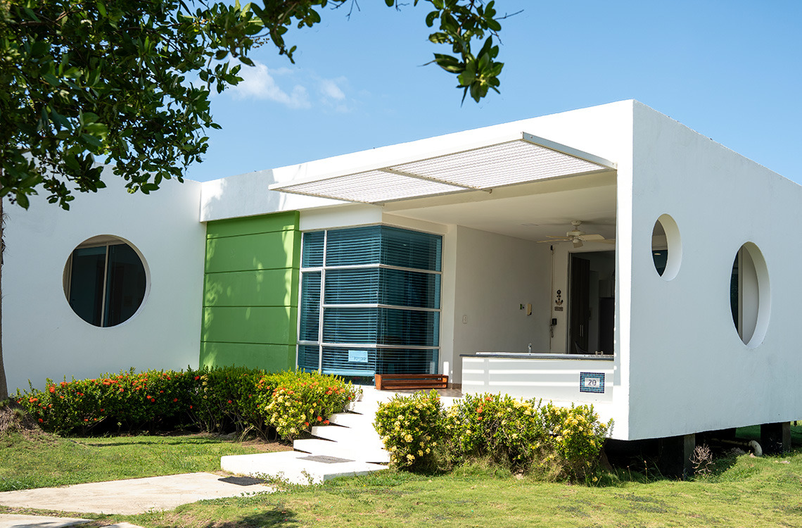 Hotel moderno con ventanas circulares y fachada verde, ideal para Marina Puerto Velero.
