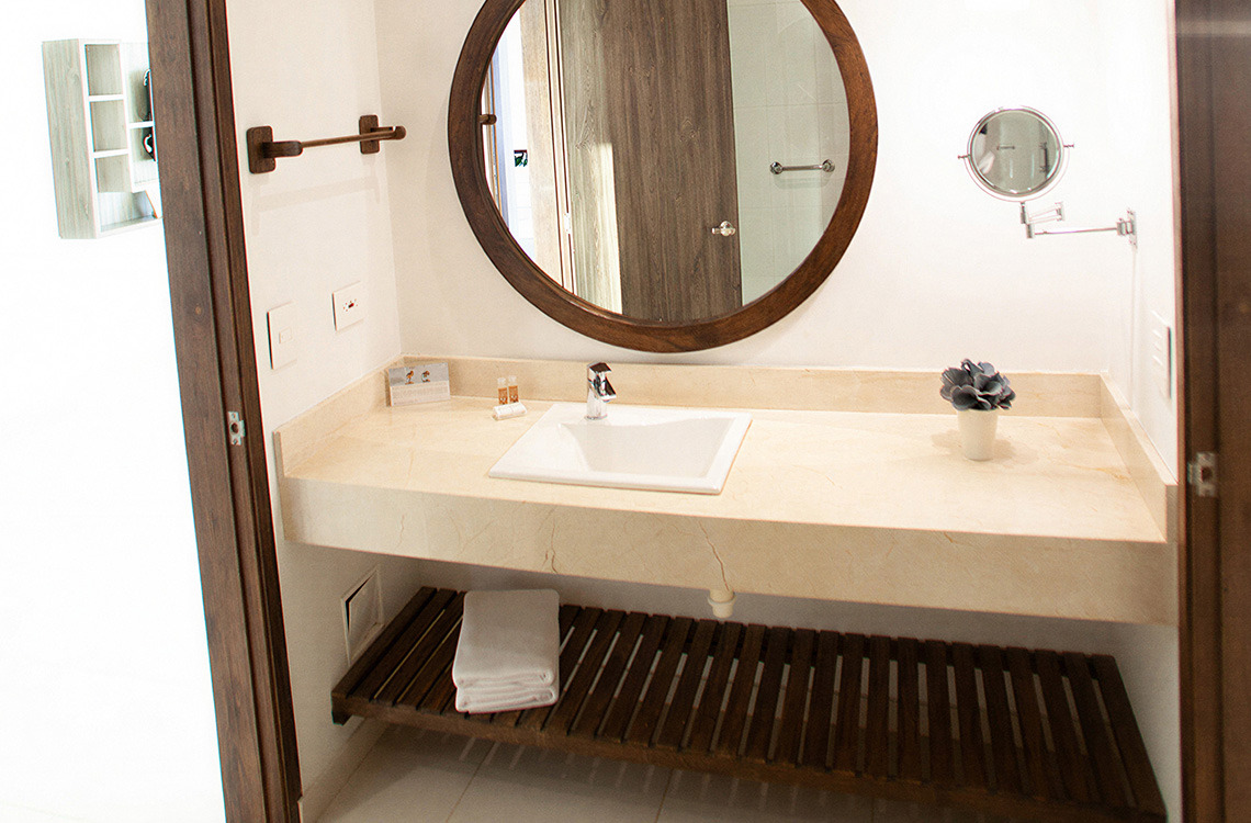 Baño moderno con lavabo empotrado, espejo redondo yMarina Puerto Velero.