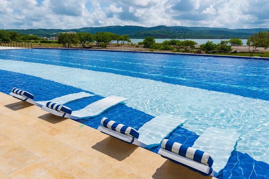 Floating loungers in infinity pool overlooking Marina Puerto Velero, perfect for relaxation.