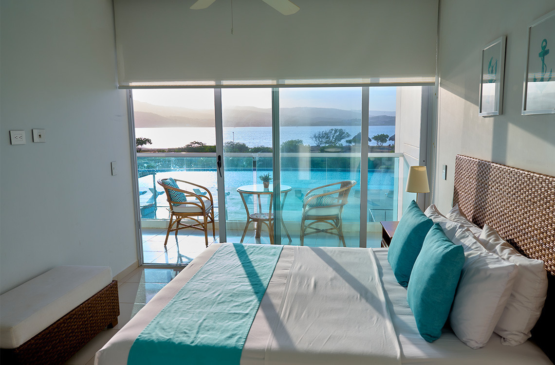 Vista al mar desde una suite de hotel con cama cómoda, balcón y sillas para disfrutar del Marina Puerto Velero.