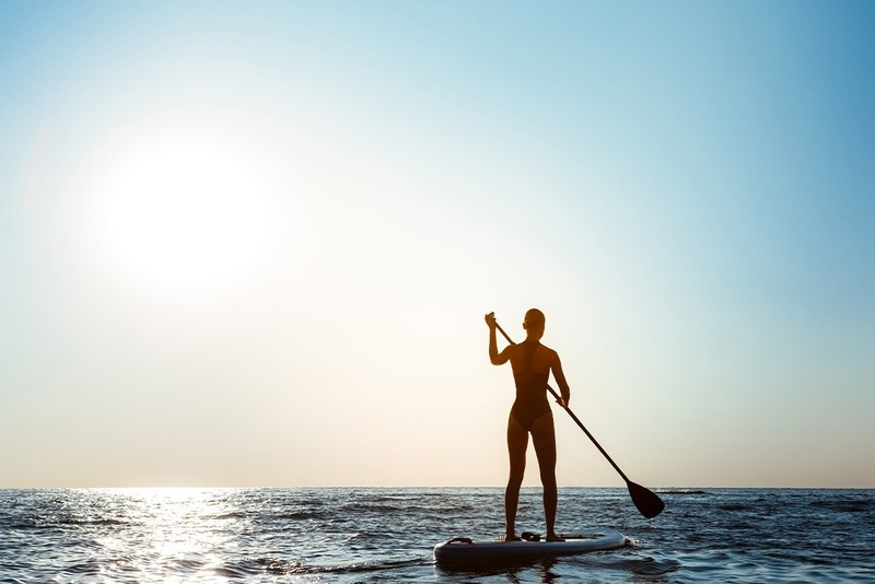 Silhouette of person paddleboarding at sunset near Marina Puerto Velero.