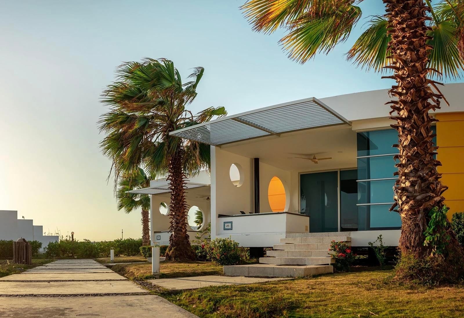 Elegantes villas en Marina Puerto Velero con palmeras y luz dorada del atardecer.