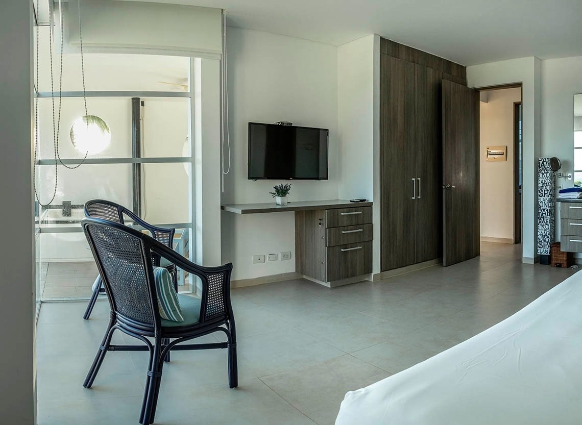 Wicker chairs by window in Marina Puerto Velero hotel room.