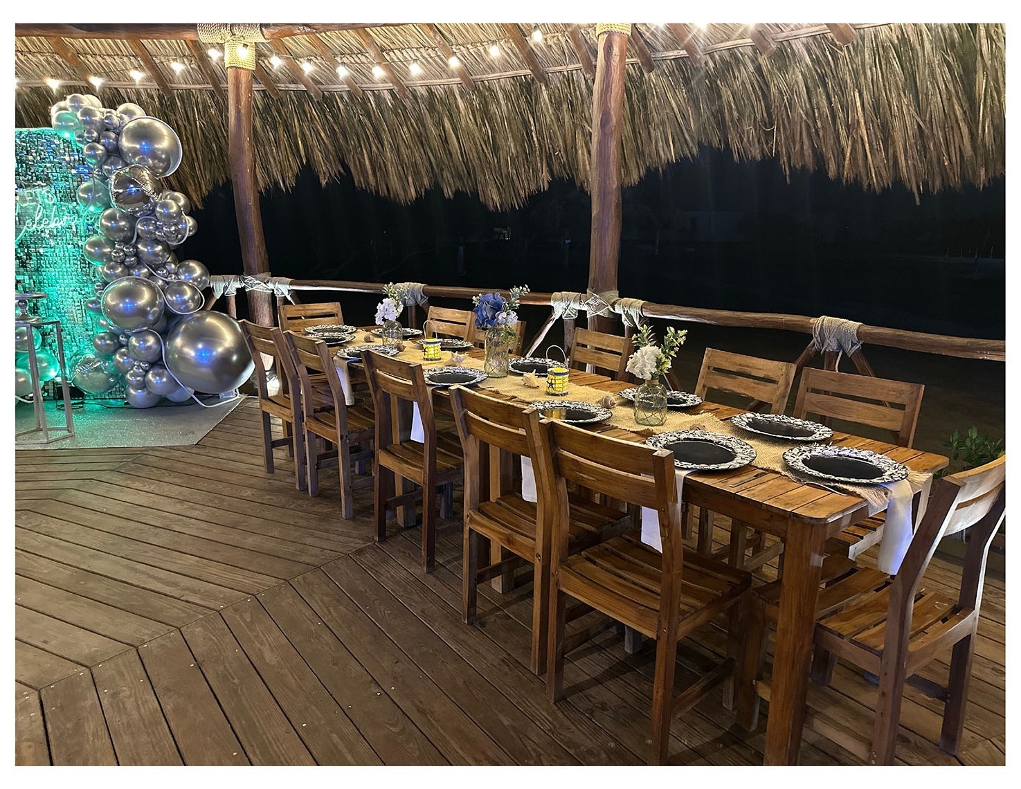 Cena al aire libre en Marina Puerto Velero, con mesa de madera decorada y globo plateado.