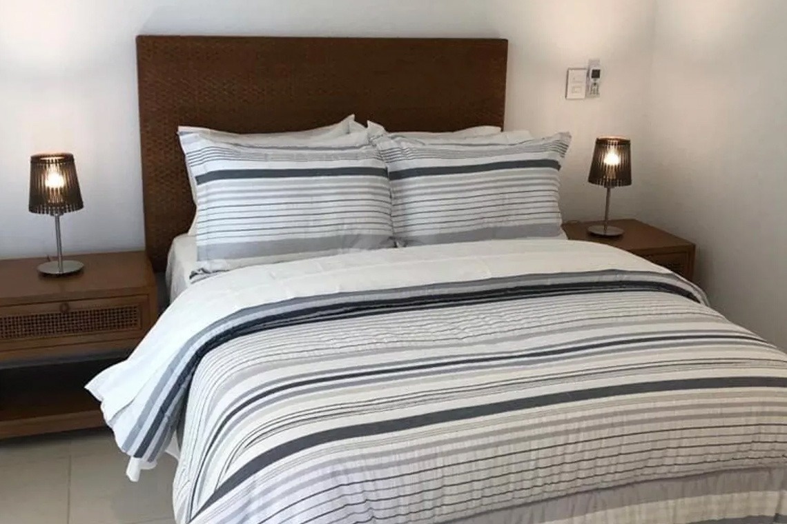 Modern hotel room with striped bedding and nightstand at Marina Puerto Velero.