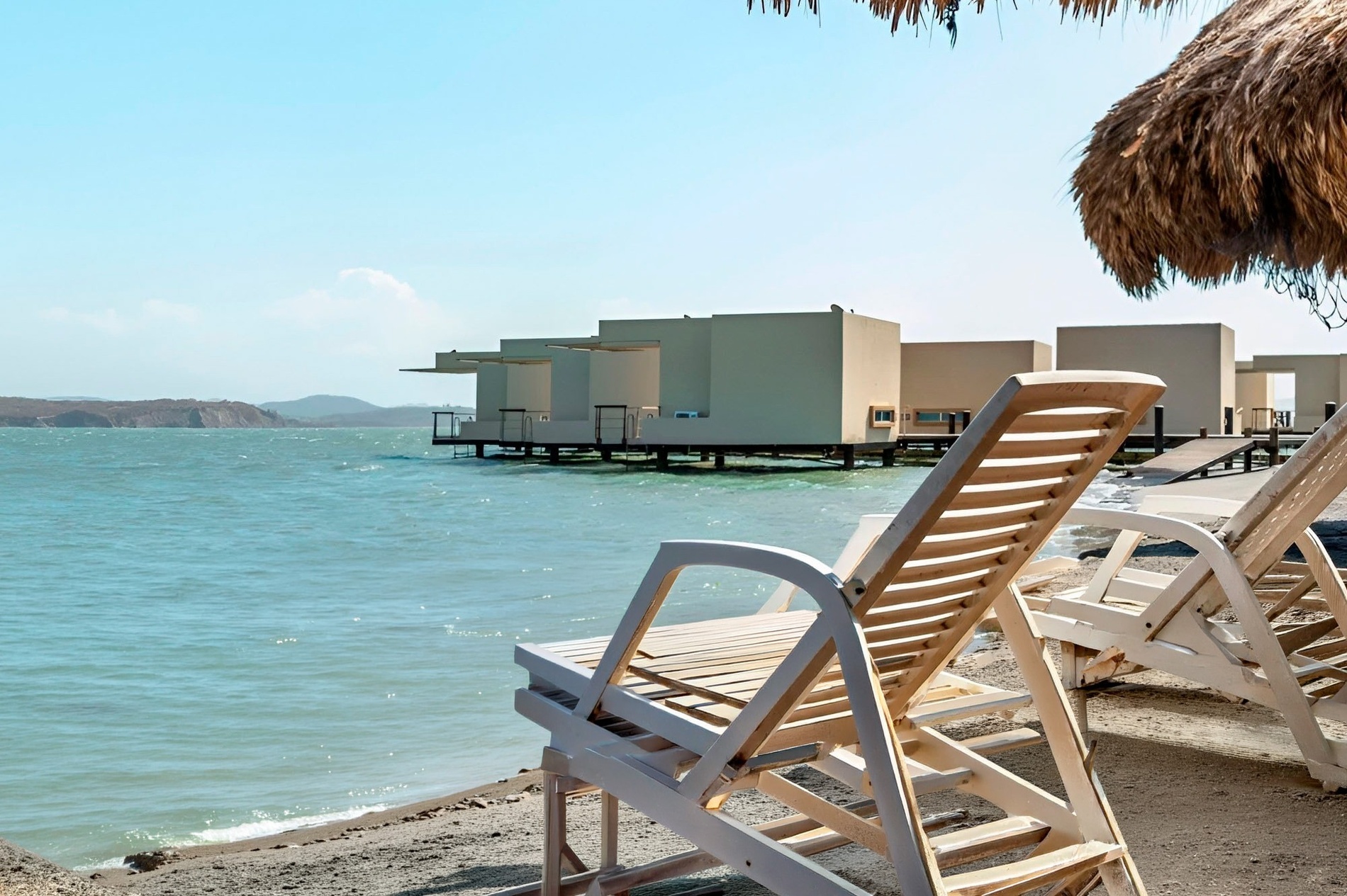 Beach loungers by overwater bungalows at Marina Puerto Velero.