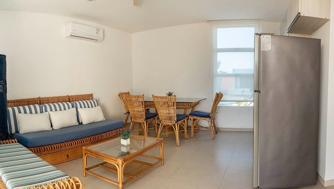 Marina Puerto Velero living and dining area with sofa, table, and refrigerator.