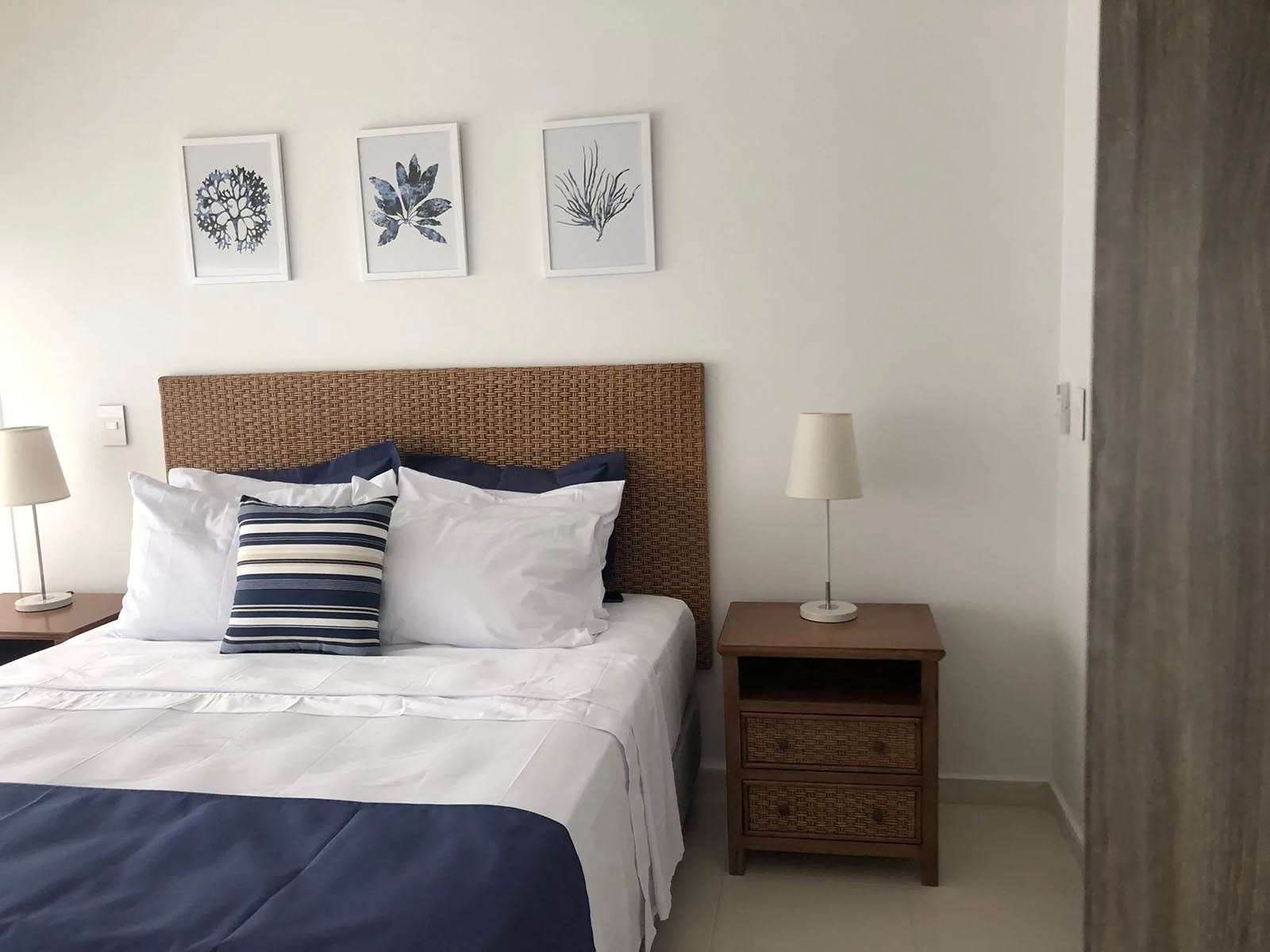 Habitación acogedora en Marina Puerto Velero con cama matrimonial, mesita de noche y arte marino.