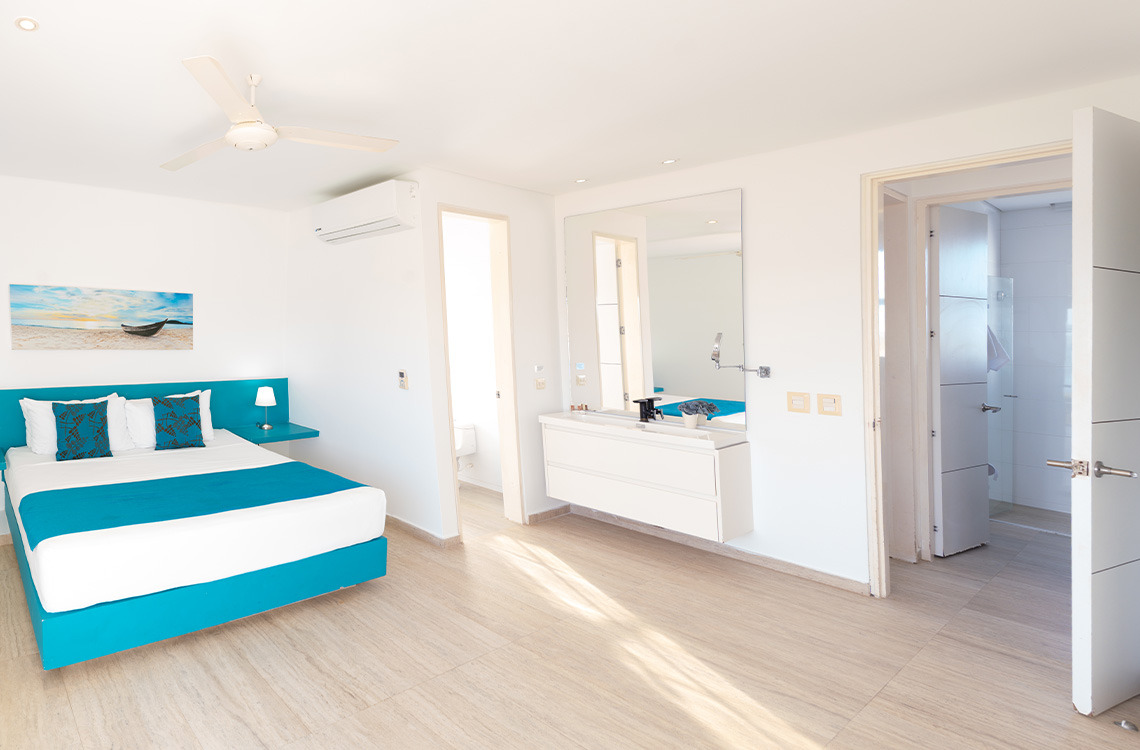 Dormitorio moderno con cama doble, aire acondicionado y baño en suite, ideal para Marina Puerto Velero.