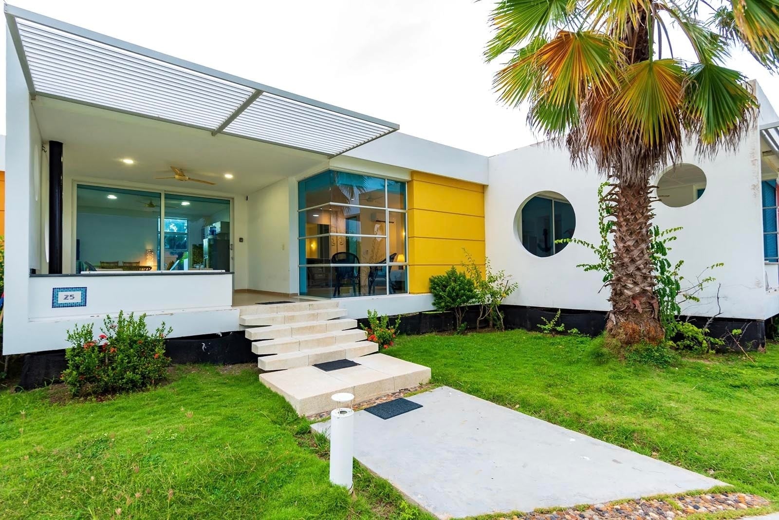 Casa moderna en Marina Puerto Velero con entrada de césped y palmera.