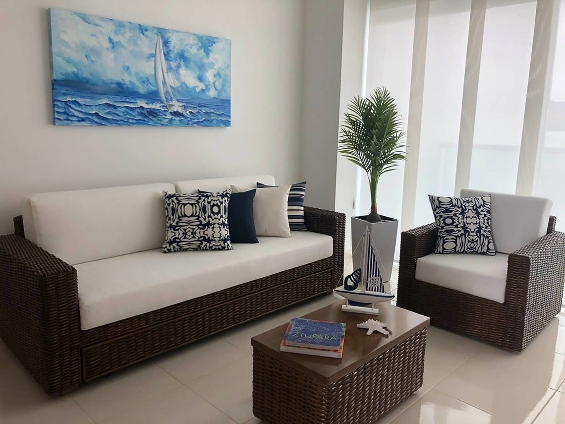 Wicker sofa and armchair in nautical-themed living room at Marina Puerto Velero.