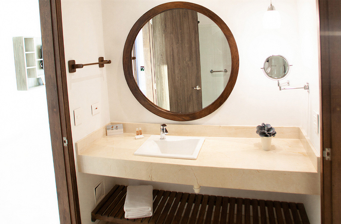 Baño moderno con lavabo, espejo redondo y accesorio Marina Puerto Velero.