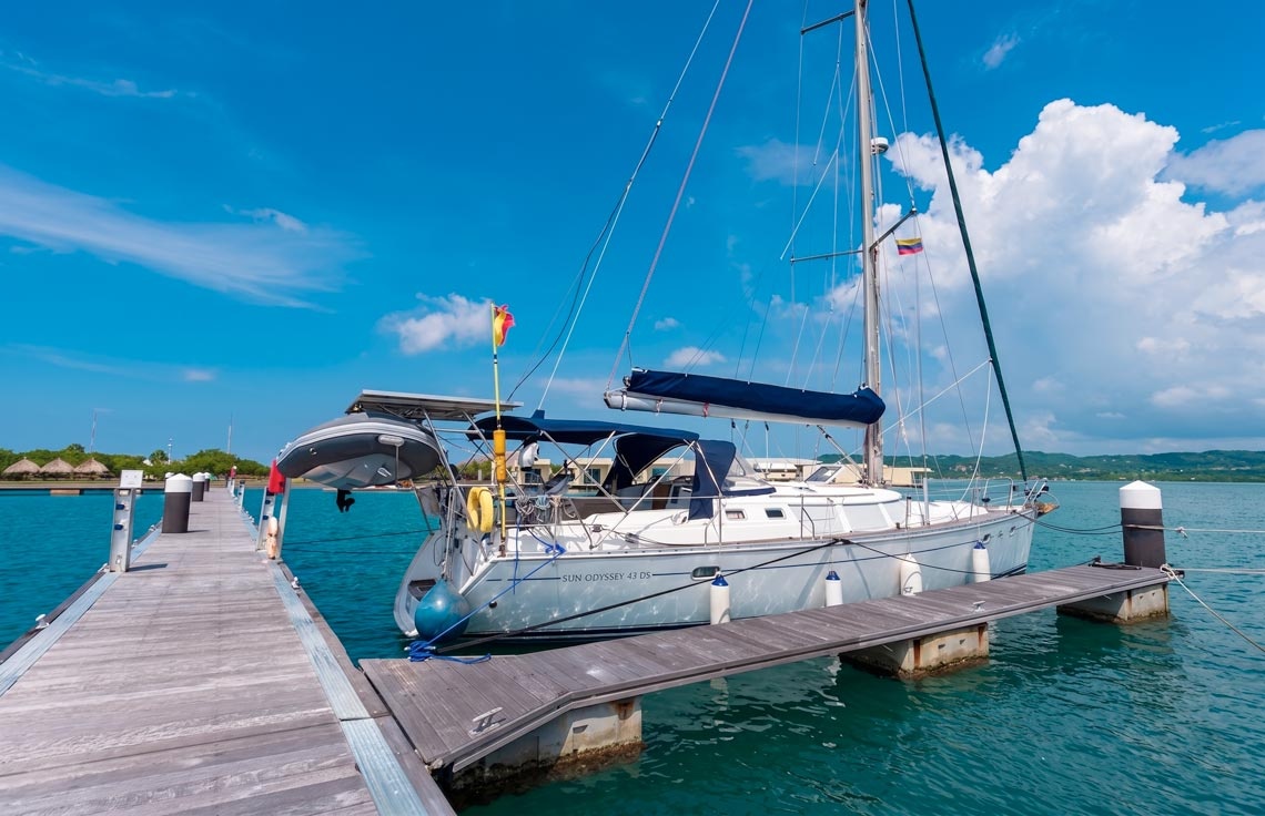 Sailboat docked at Marina Puerto Velero under a vibrant blue sky.