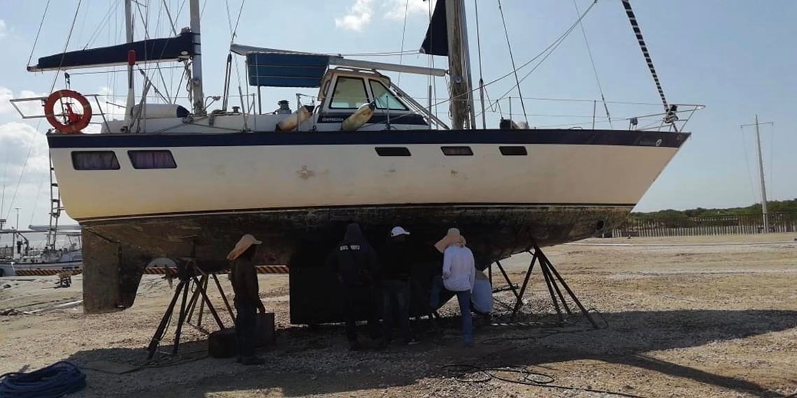Boat in dry dock at Marina Puerto Velero, with crew working on maintenance.